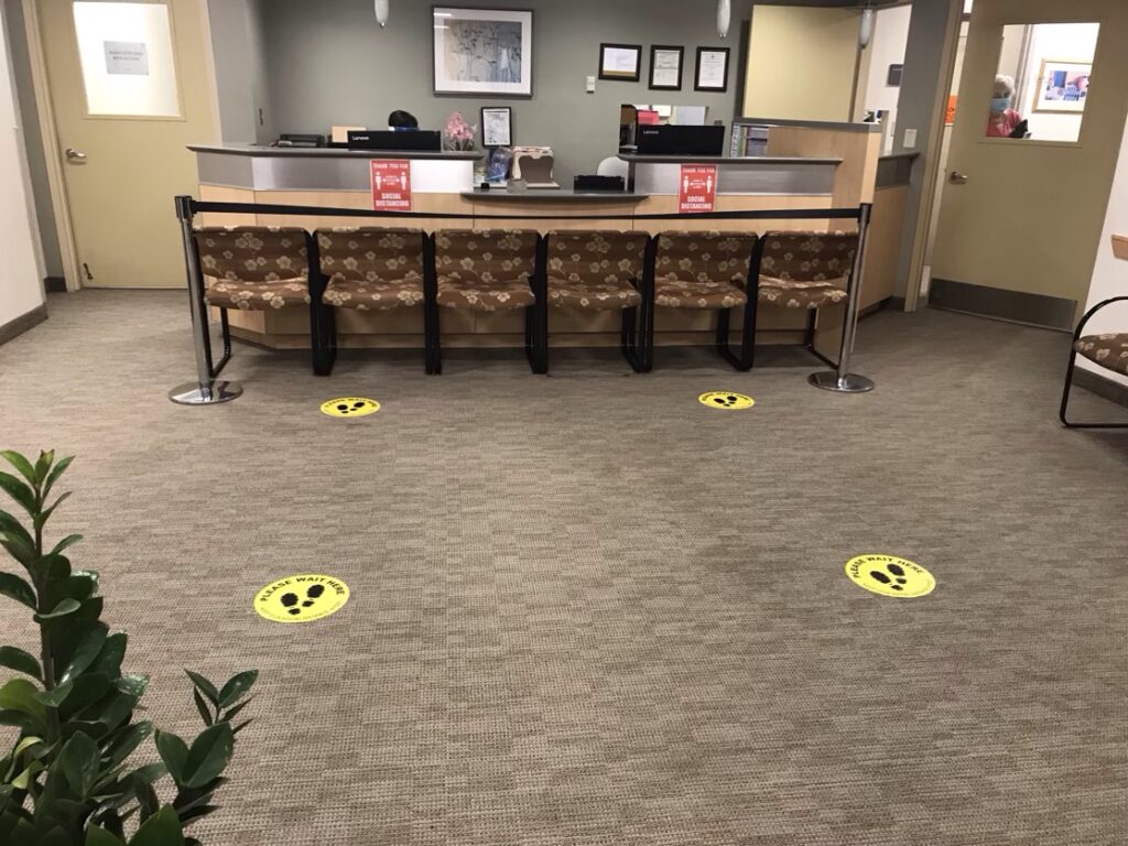 Photo of a reception desk with social distancing stickers on the floor